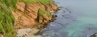 Elevated panoramic view of a bay with red sandstone cliffs in the Chatham islands New Zealand