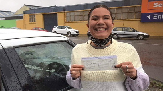 Danni, with a large smile, holding up a driver licence. 